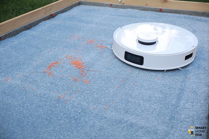 Ecovacs Deebot T10 reinigt Linsen auf einem Teppich im Saugtest.